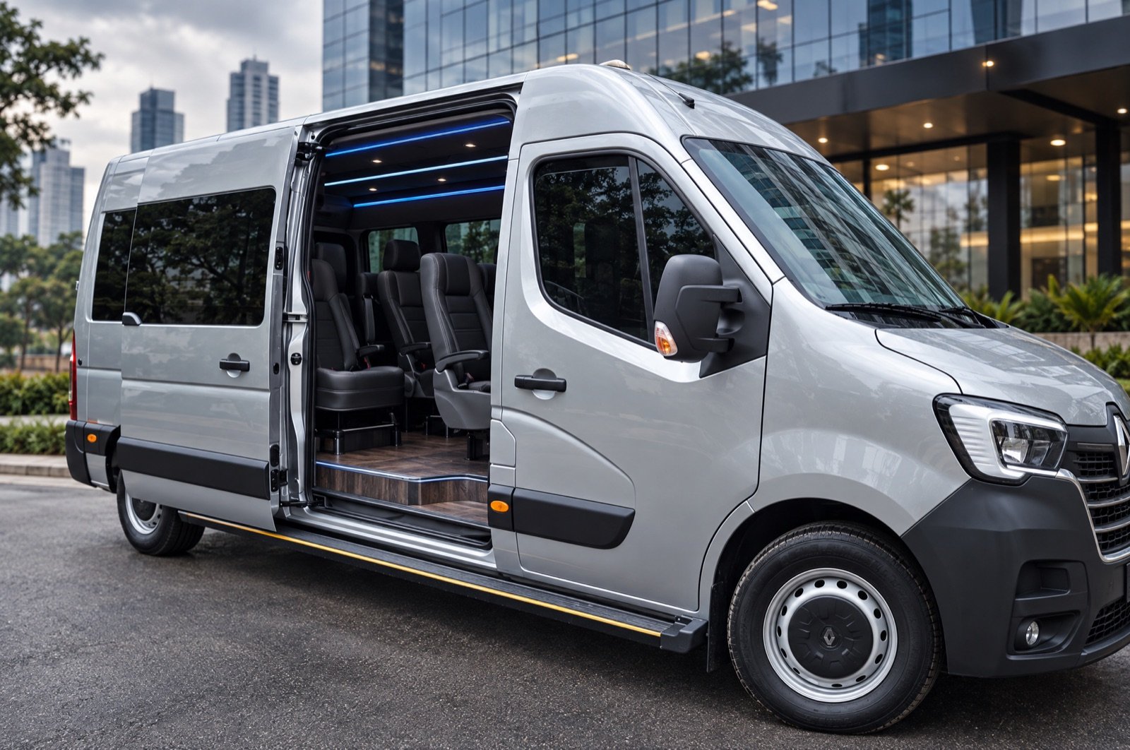 Van executiva prata Renault Master com a porta lateral aberta, mostrando poltronas de couro, estacionada em frente a um edifício corporativo.